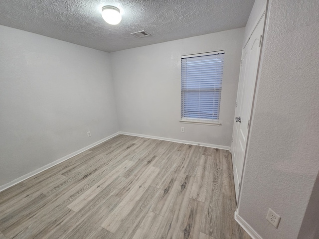 spare room featuring light hardwood / wood-style flooring and a textured ceiling