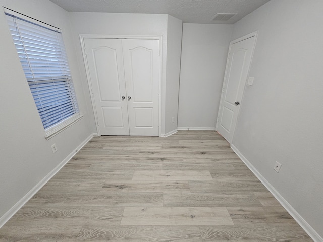 unfurnished bedroom with light wood-type flooring and a closet