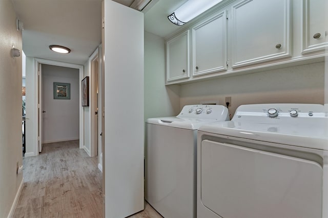 laundry area featuring cabinets, light wood-type flooring, and washing machine and clothes dryer