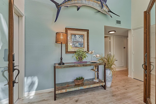 foyer entrance featuring light hardwood / wood-style floors and a high ceiling