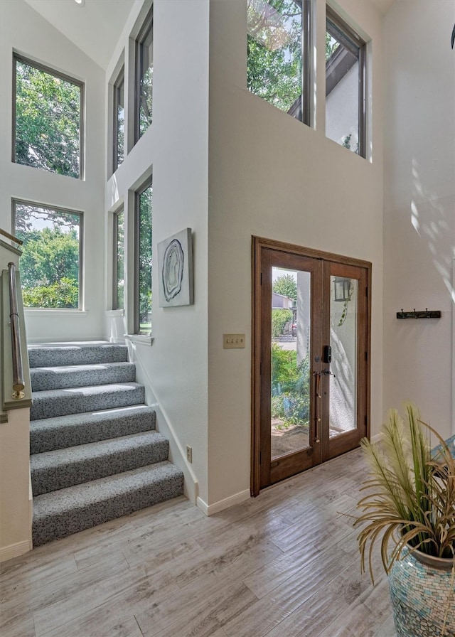 foyer with french doors, a high ceiling, and light wood-type flooring