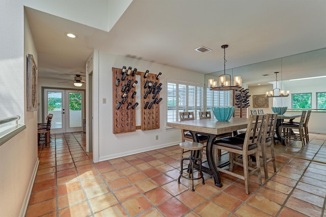 dining room with ceiling fan with notable chandelier, light tile patterned floors, and french doors