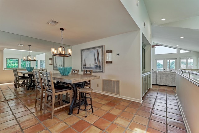 tiled dining room with french doors, an inviting chandelier, and lofted ceiling