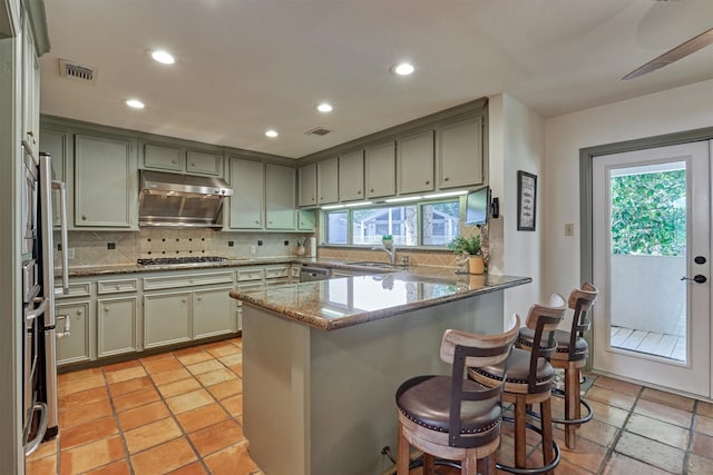 kitchen with sink, a breakfast bar area, light stone counters, kitchen peninsula, and stainless steel appliances