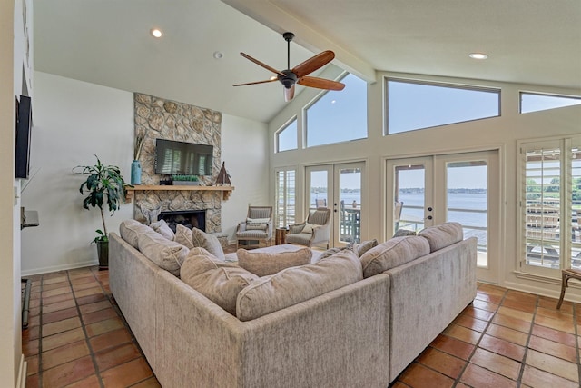 tiled living room with vaulted ceiling with beams, ceiling fan, a fireplace, and french doors