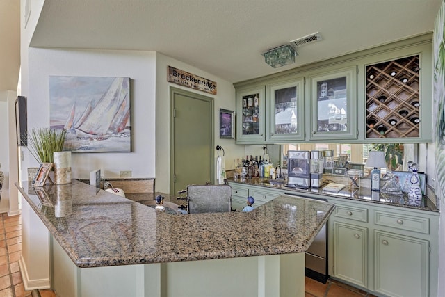 kitchen with kitchen peninsula, green cabinets, light tile patterned flooring, and stone countertops