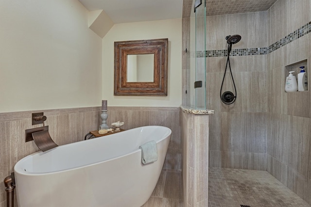 bathroom featuring shower with separate bathtub and tile walls