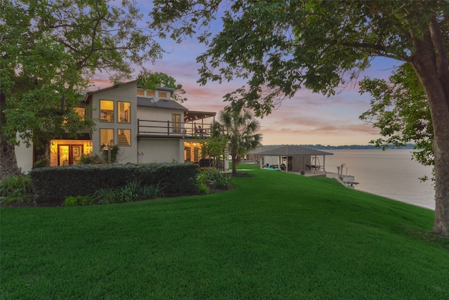 yard at dusk featuring a gazebo, a water view, and a balcony