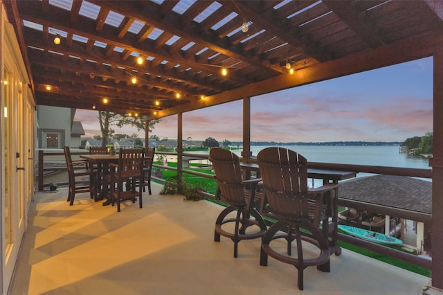 patio terrace at dusk featuring a water view