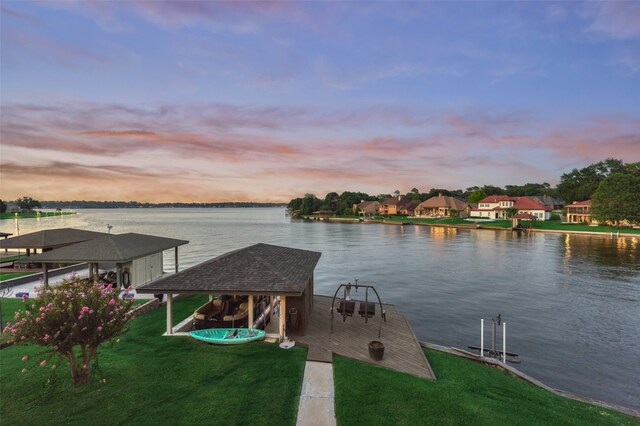 view of dock with a water view and a lawn