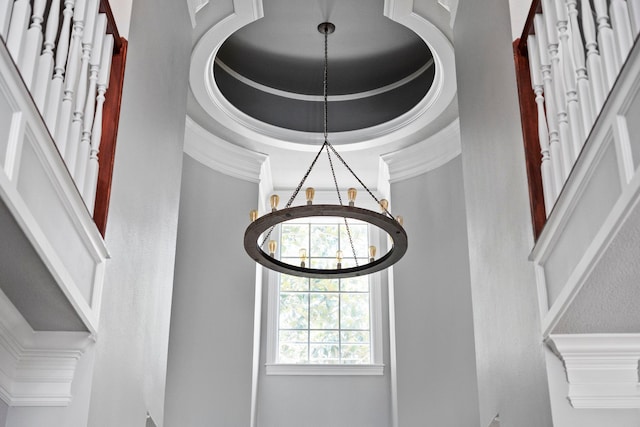 details featuring a raised ceiling, a chandelier, and ornamental molding