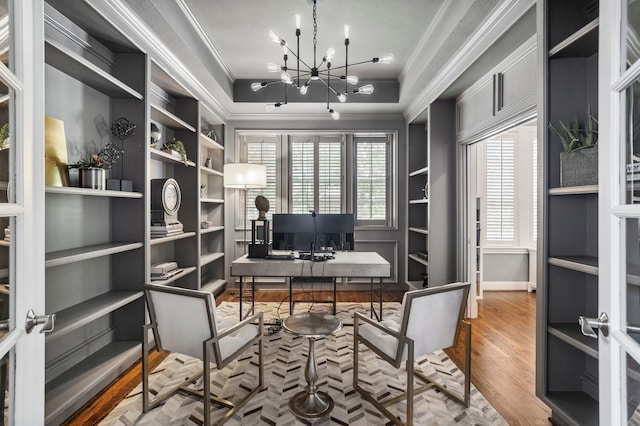 office featuring hardwood / wood-style flooring, a notable chandelier, built in features, and ornamental molding