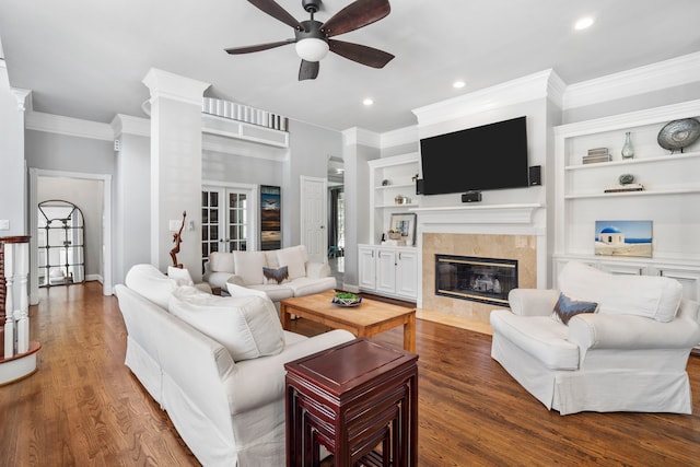 living room featuring a tile fireplace, ceiling fan, dark hardwood / wood-style flooring, and ornamental molding