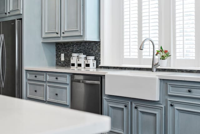 kitchen featuring tasteful backsplash, gray cabinetry, sink, and appliances with stainless steel finishes