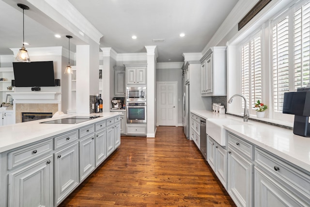 kitchen featuring sink, crown molding, appliances with stainless steel finishes, decorative light fixtures, and dark hardwood / wood-style flooring