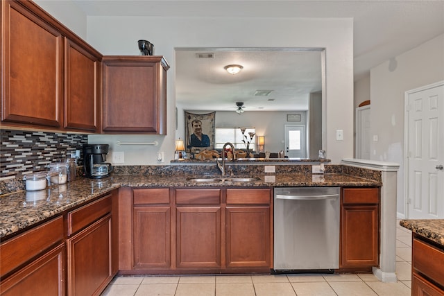 kitchen featuring stainless steel dishwasher, tasteful backsplash, sink, dark stone countertops, and light tile patterned floors