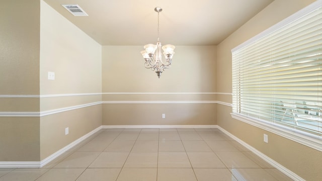 empty room featuring tile patterned floors and an inviting chandelier