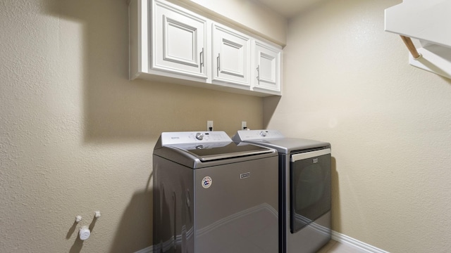 clothes washing area featuring washing machine and dryer and cabinets