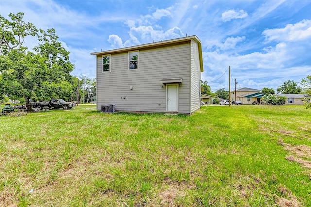 back of house with central air condition unit and a yard