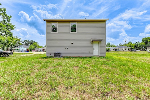 back of house featuring central AC unit and a lawn