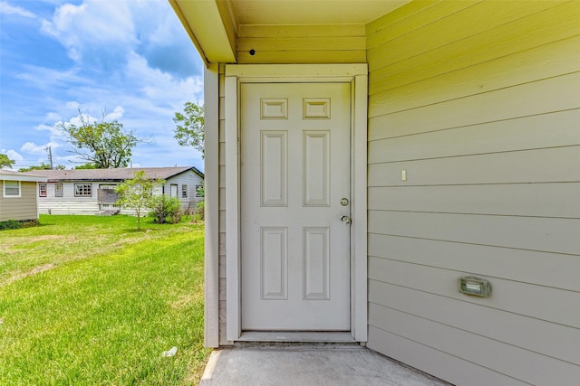 view of exterior entry featuring a lawn