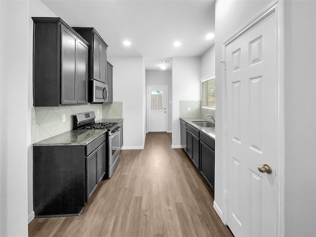 kitchen with light stone countertops, appliances with stainless steel finishes, tasteful backsplash, and sink