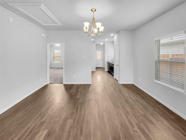 unfurnished living room with a chandelier and dark wood-type flooring