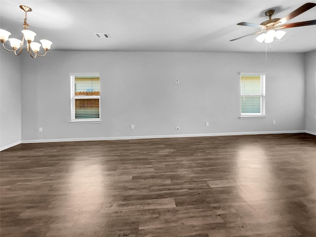 empty room featuring ceiling fan with notable chandelier, a wealth of natural light, and dark hardwood / wood-style floors