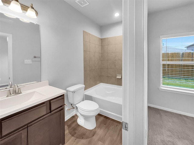 full bathroom with toilet, wood-type flooring, vanity, and tiled shower / bath