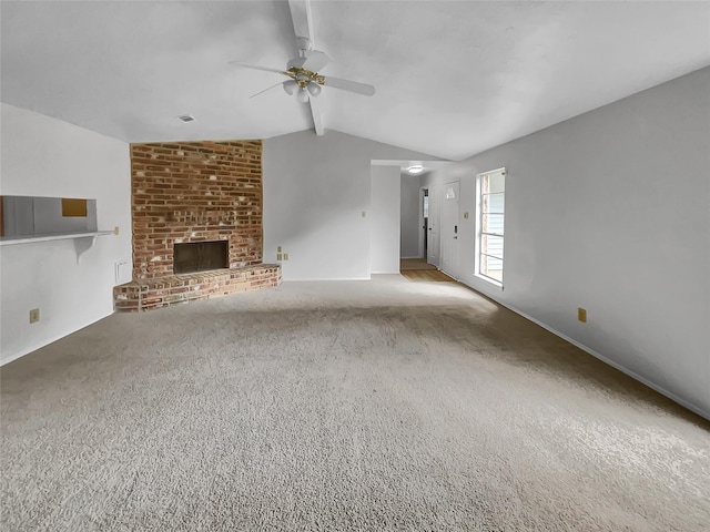 unfurnished living room featuring ceiling fan, a brick fireplace, carpet flooring, and lofted ceiling with beams