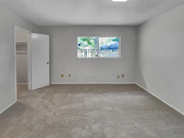 unfurnished bedroom with light carpet, a closet, and a walk in closet