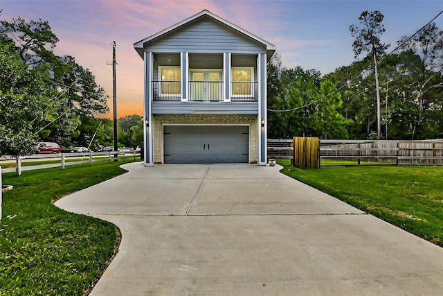 view of front facade with a yard, a balcony, and a garage