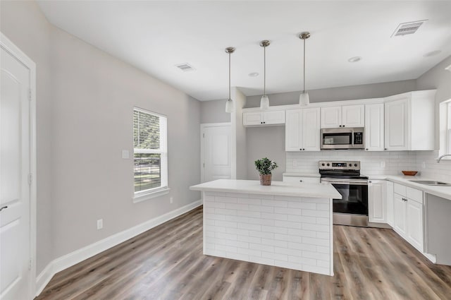 kitchen with white cabinets, appliances with stainless steel finishes, a kitchen island, and sink