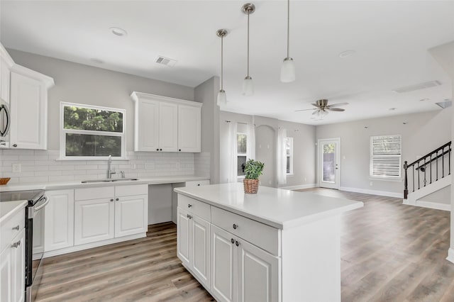 kitchen with a center island, white cabinets, sink, ceiling fan, and electric range oven