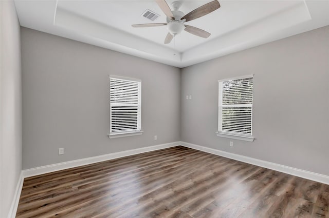 unfurnished room featuring ceiling fan, a raised ceiling, and dark wood-type flooring