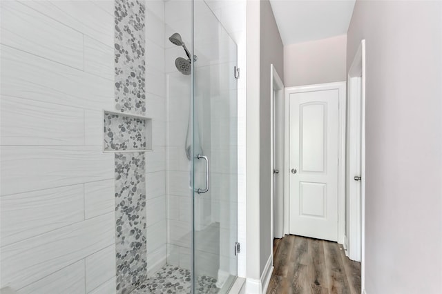 bathroom featuring a shower with shower door and wood-type flooring