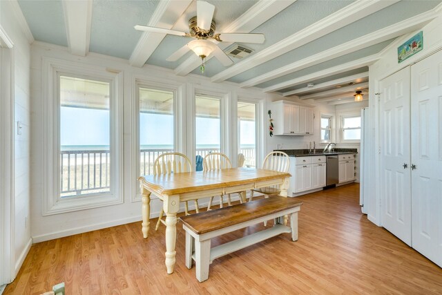 dining space with light hardwood / wood-style floors, a wealth of natural light, and beam ceiling