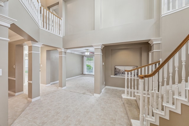 foyer entrance with light carpet, a high ceiling, ceiling fan, and decorative columns