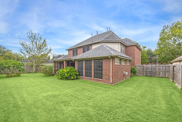 rear view of property featuring a lawn and a sunroom