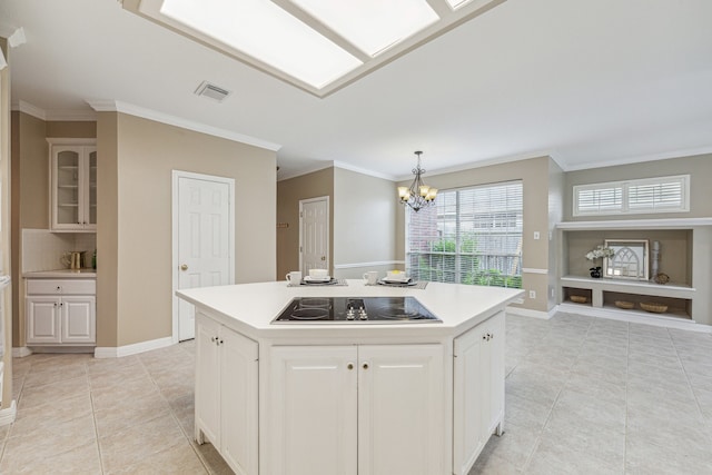 kitchen featuring an island with sink, crown molding, decorative light fixtures, black electric stovetop, and a notable chandelier