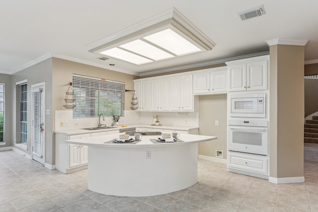 kitchen with a kitchen island, backsplash, white appliances, and white cabinetry