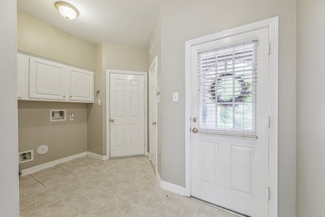 washroom with hookup for a washing machine, cabinets, light tile patterned floors, and a textured ceiling