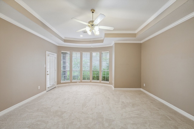 carpeted empty room featuring a tray ceiling, ceiling fan, and crown molding