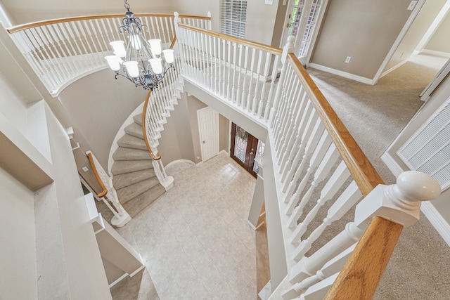 stairs with carpet floors, a high ceiling, and an inviting chandelier