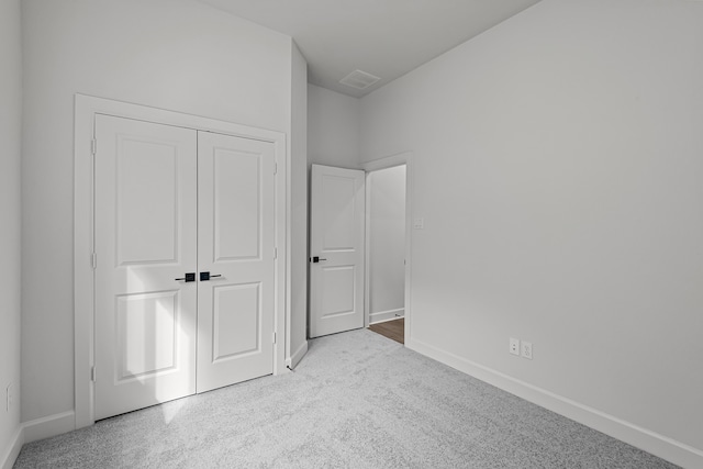 unfurnished bedroom with light carpet and a closet