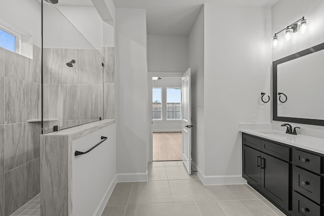 bathroom with a tile shower, vanity, and tile patterned floors