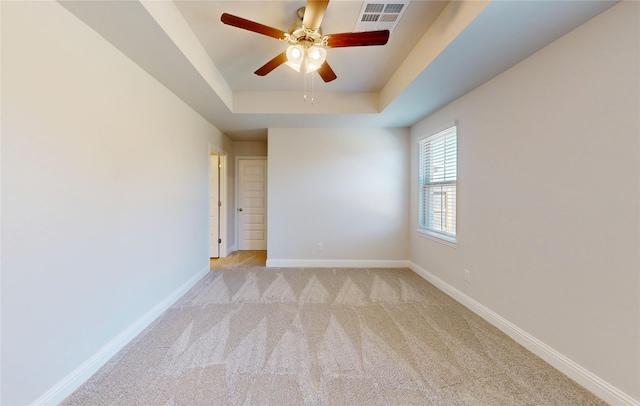 19910 Paros Island Dr, Hockley, TX 77447 - empty room with a ceiling fan, visible vents, baseboards, a tray ceiling, and light carpet
