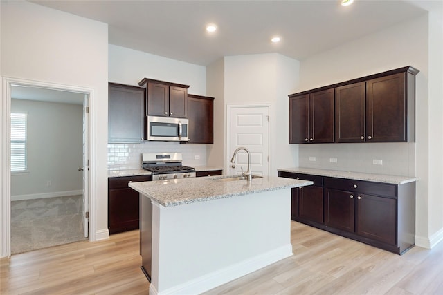19910 Paros Island Dr, Hockley, TX 77447 - kitchen featuring a sink, decorative backsplash, stainless steel appliances, dark brown cabinets, and light wood-type flooring