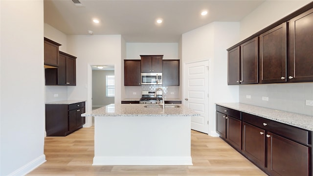 19910 Paros Island Dr, Hockley, TX 77447 - kitchen featuring a center island with sink, stainless steel appliances, light wood-style floors, and a sink