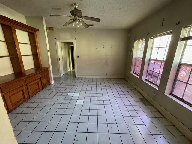 tiled spare room featuring a textured ceiling and ceiling fan